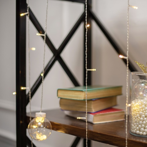 Even your nondescript bookcase can become sparkling with a string of lights.